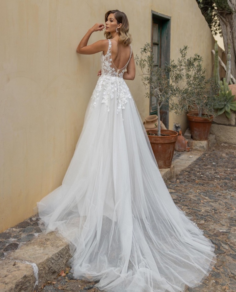 Rückenansicht eines Boho-Brautkleides in A-Linie mit V-Ausschnitt am Rücken, floralen Spitzenapplikationen und leichter Schleppe, vom Brautladen Brittanja aus Moers.