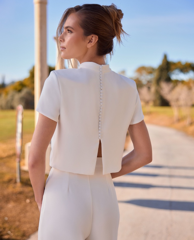 Rückenansicht eines modernen Braut-Jumpsuits mit minimalistischem Design, kurzen Ärmeln und einer feinen Knopfleiste am Rücken, von Brittanja in Moers.