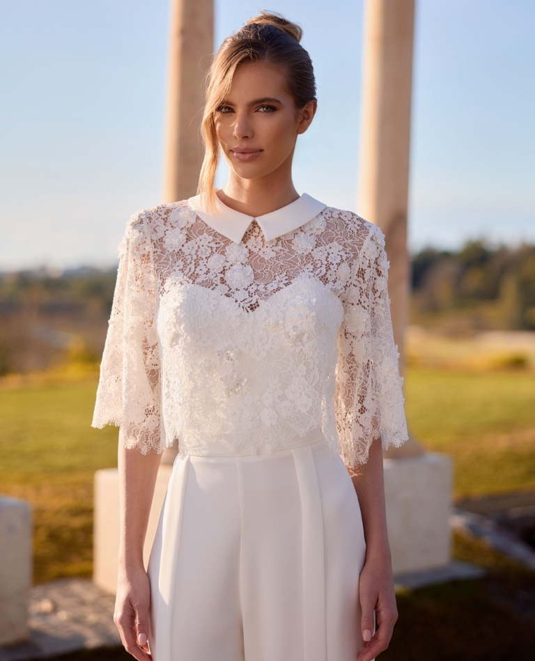 Eleganter weißer Braut-Jumpsuit für das Standesamt mit einem filigranen Spitzenoberteil, Bubikragen und weiter Hose, vom Brautladen Brittanja aus Moers.