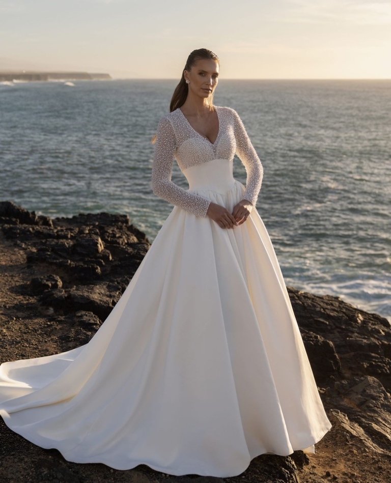 Hochwertiges Clean-Chic Brautkleid aus glänzendem Satin mit langen Ärmeln und aufwendigem Perlenbesatz am Oberteil, von Brittanja Moers.