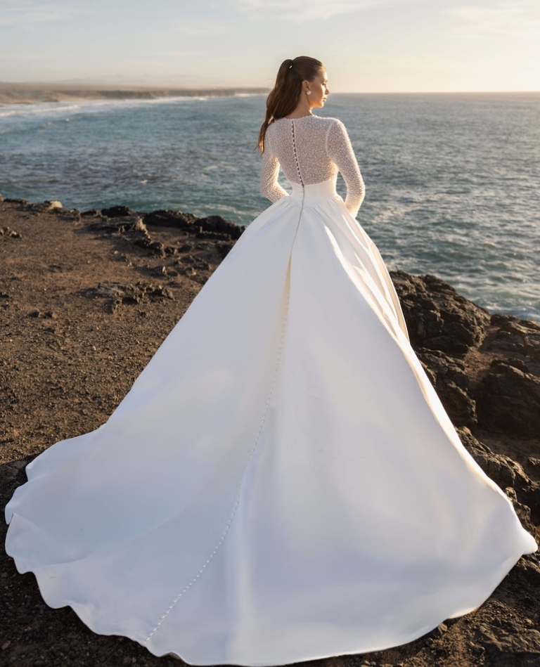 Rückenansicht eines herrschaftlichen Satin-Brautkleides mit langer Schleppe und durchgehender Knopfleiste, präsentiert vom Brautladen Brittanja in Moers.