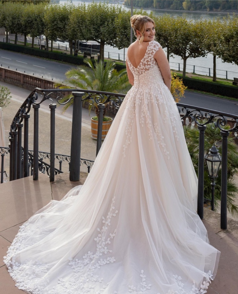 Rückenansicht eines Curvy-Brautkleides in A-Linie mit floraler Spitze, tiefem Rückenausschnitt und eleganter Schleppe, vom Brautladen Brittanja aus Moers.