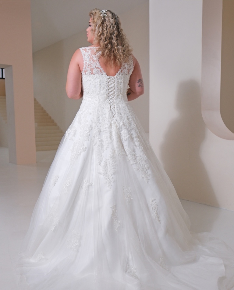 Rückenansicht eines Curvy-Brautkleides in A-Linie mit transparenter Spitze am Rücken, klassischer Korsett-Schnürung und fließender Schleppe, vom Brautladen Brittanja aus Moers