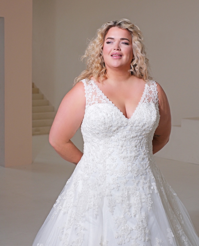 Romantisches A-Linien Brautkleid für Curvy-Bräute mit elegantem V-Ausschnitt und durchgehender floraler Spitzenverzierung, vom Brautladen Brittanja aus Moers.
